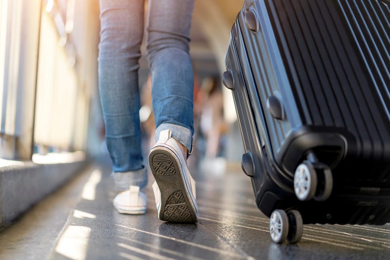 traveler wearing tennis shoes pulling suitcase