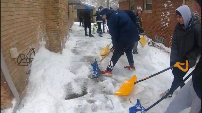 A group of teenage boys shoveling snow 