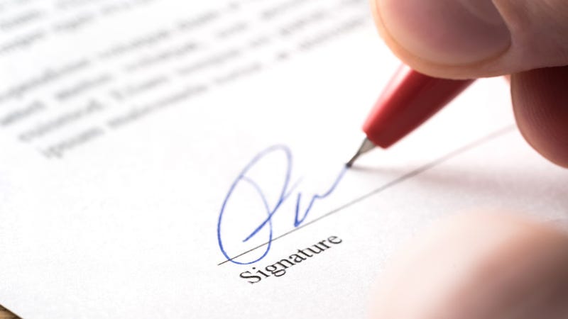 Man writing name and autograph with pen