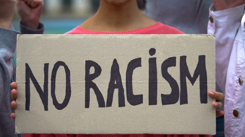 Girl holds sign reading 'No racism'