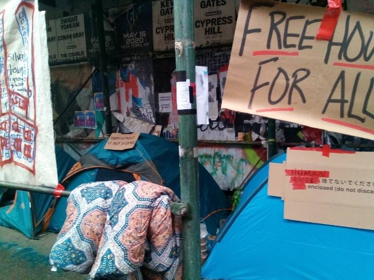 Signs advocating for better housing access adorn the encampment on Wednesday morning before the sweep.