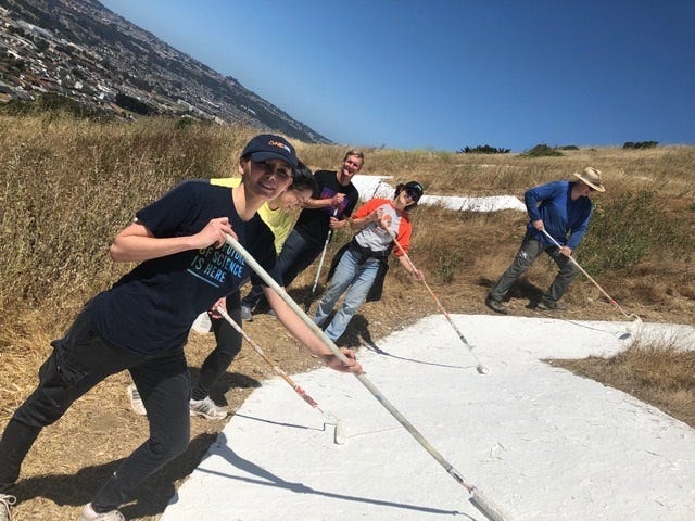 Genentech volunteers painting South San Francisco hillside sign Friday morning