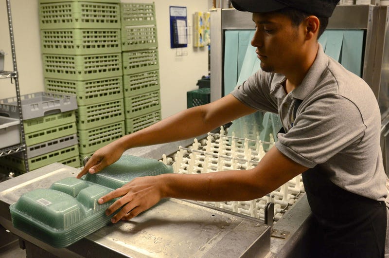 Antoni Fajaro, student from Los Angeles, washes re-usable go containers that students used to fill with food, then they are inserted into the OZZI machine which refunds the $5 deposit on the tray.
