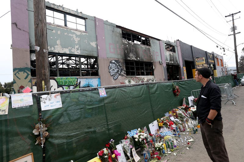 A mourner pays his respects as Investigators carry on their work at the Ghost Ship warehouse in Oakland, Calif., on December 13, 2016.