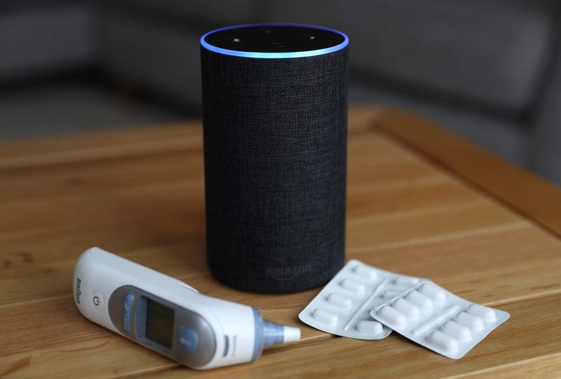 A general view of an Amazon Echo smart speaker alongside an ear thermometer and some pills