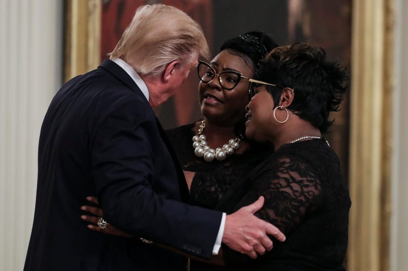 President Donald Trump hugs conservative social media figure Rochelle Richardson, known as Silk of "Diamond and Silk" as she and Lynnette Hardaway, known as Diamond, come on to the stage at the president's invitation at his social media summit with promin