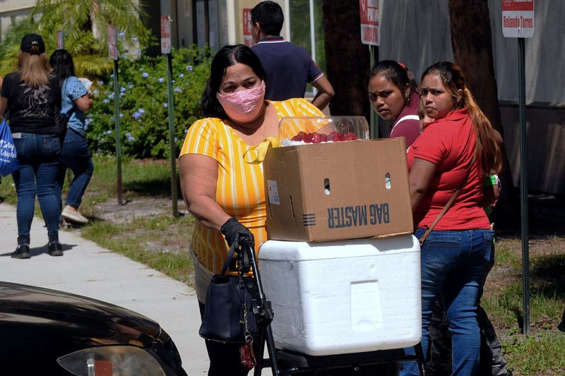 A woman pushes a walker loaded with food assistance provided by the Second Harvest Food Bank of Central Florida at a food distribution event staffed by volunteers at the Calvario City Church. Photo by Paul Hennessy / SOPA Images/Sipa USA)