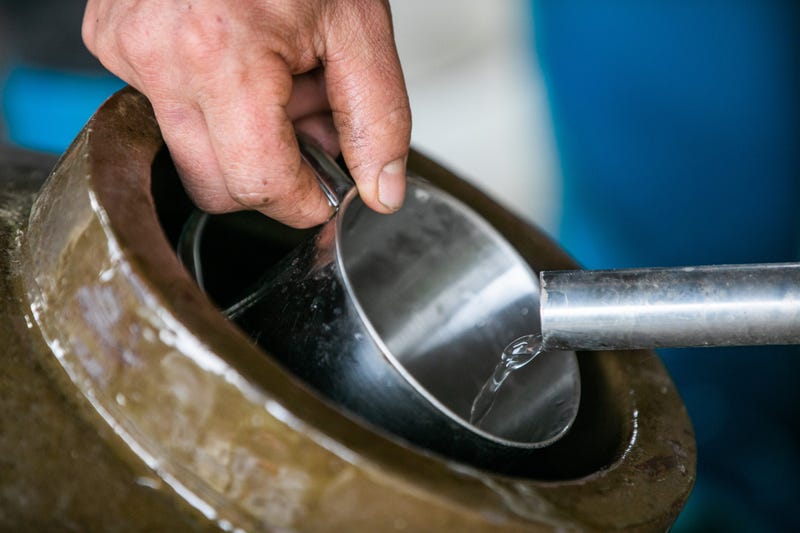 BIJIE, CHINA - DECEMBER 8, 2020 - A villager checks the strength of newly distilled liquor at a liquor workshop in Bijie, Guizhou Province, China, Dec. 8, 2020. (Photo by Luo Dafu / Costfoto/Sipa USA)