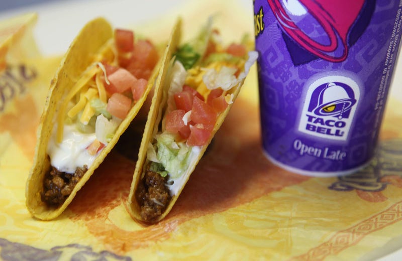 Two hard shell tacos leaning against a soda cup bearing the Taco Bell logo