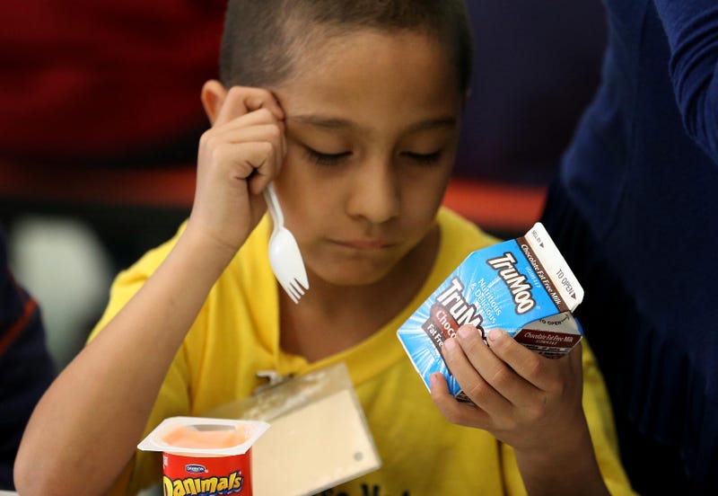 A boy at school inspects his carton of chocolate milk
