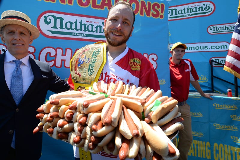 Helped by MC George Shea, Joey "Jaws" Chestnut holds a platter of 70 hot dogs in ten minutes representing the number consumed during Nathan's Famous 100th Anniversary of the 4th of July hot dog-eating contest at Coney Island in the New York City borough of Brooklyn, NY, on July 4, 2016. This is Mr. Chestnut's ninth Nathan's Famous championship title.
