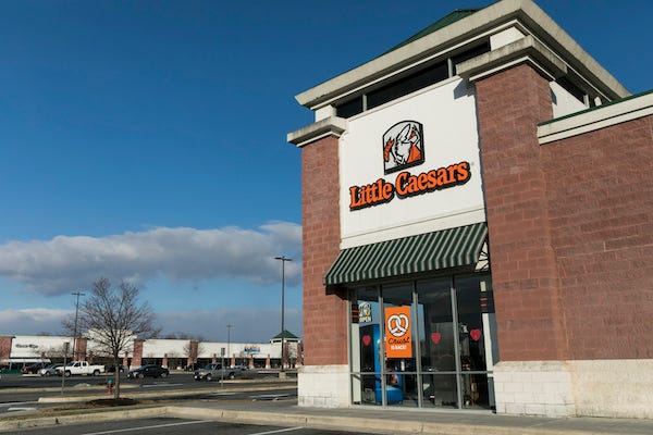 A logo sign outside of a Little Caesars restaurant location