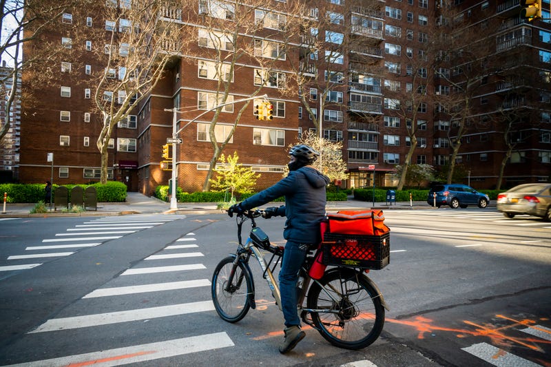 A delivery person with a DoorDash branded tote on his bicycle in Chelsea