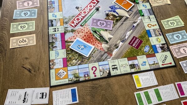 The board game Monopoly being played on a wooden table