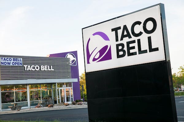 A logo sign outside of a Taco Bell restaurant location in Winchester, Virginia