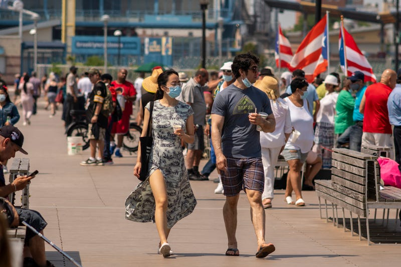 Beachgoers generally observe social distancing and wear masks on the boardwalk as they try to beat the heat and humidity at Coney Island in Brooklyn in New York on the long Independence Day weekend.