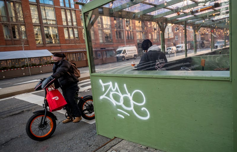 A delivery person with a DoorDash branded tote on his bicycle next to an al fresco dining structure in the Chelsea neighborhood of New York on Wednesday, January 6, 2021