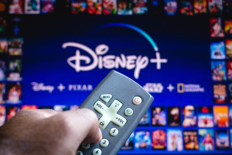 In this photo illustration a person holding a TV remote control and the Disney+ (Plus) logo in the background. (Photo by Rafael Henrique / SOPA Images/Sipa USA)