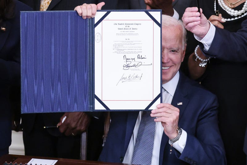  President Joe Biden (right) holds a signed Juneteenth National Independence Day Act into law in the East Room of the White House on June 17, 2021 in Washington, DC.