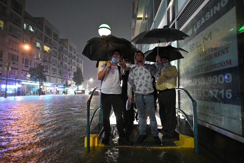 People stand at a subway entrance as they debate to wade through several inches of water caused flash flooding after remnants of storm Ida brought three inches of rain per hour across the city, in the New York City borough of Queens, NY, September 1, 2021