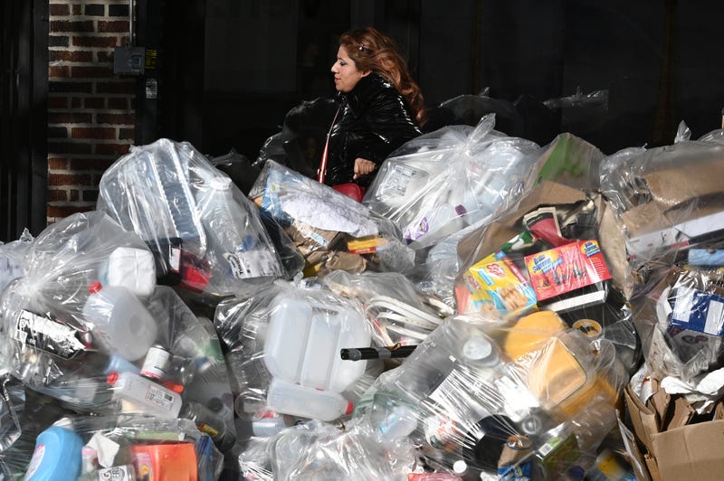 A woman walks past a pile of garbage along 43rd Avenue in Queens on Nov. 3, 2021