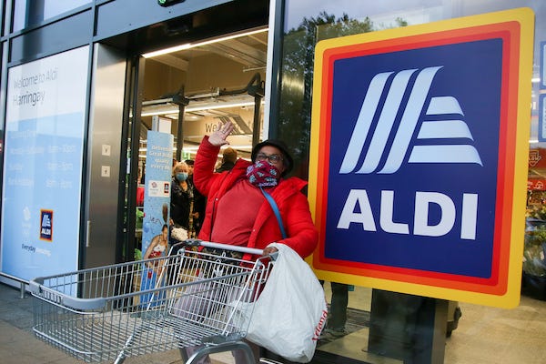 A shopper waves outside Aldi supermarket