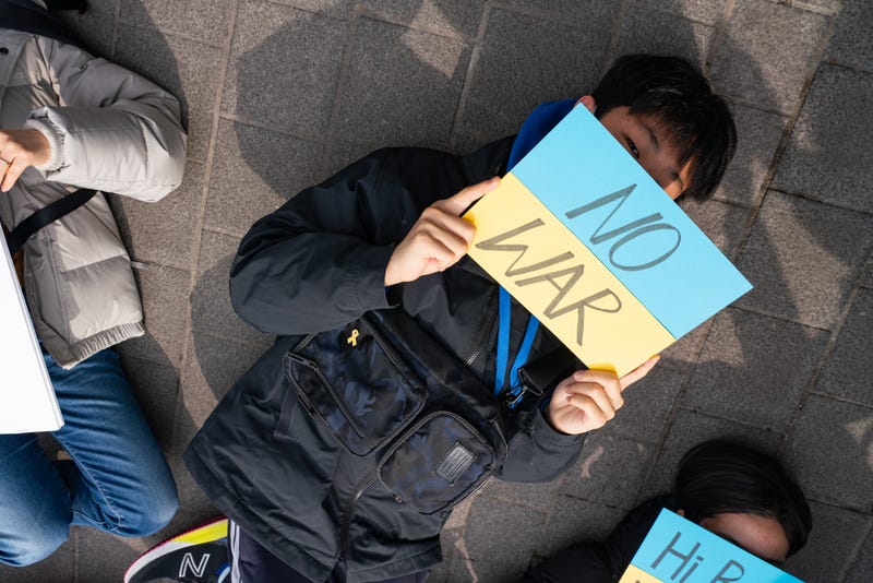 A protestor holding a placard saying 'No War' lies down during a protest against Russia's attack in Ukraine outside of Russian embassy in Seoul.