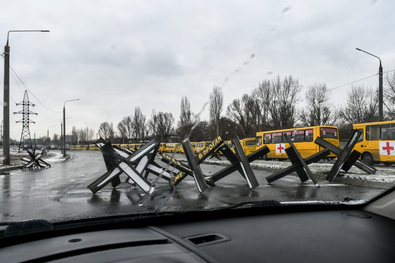 Anti-tank obstacles, known as Czech hedgehogs, block a street near a convoy of buses in Zaporizhzhia ready to take off for besieged Mariupol to deliver humanitarian aid on March 6