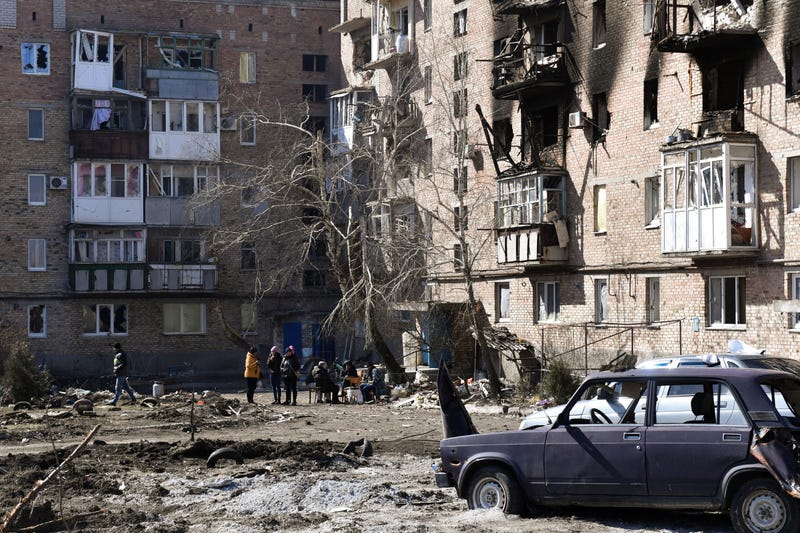 Local residents are seen outside an apartment block where the basement is used as a bomb shelter in the city of Volnovakha
