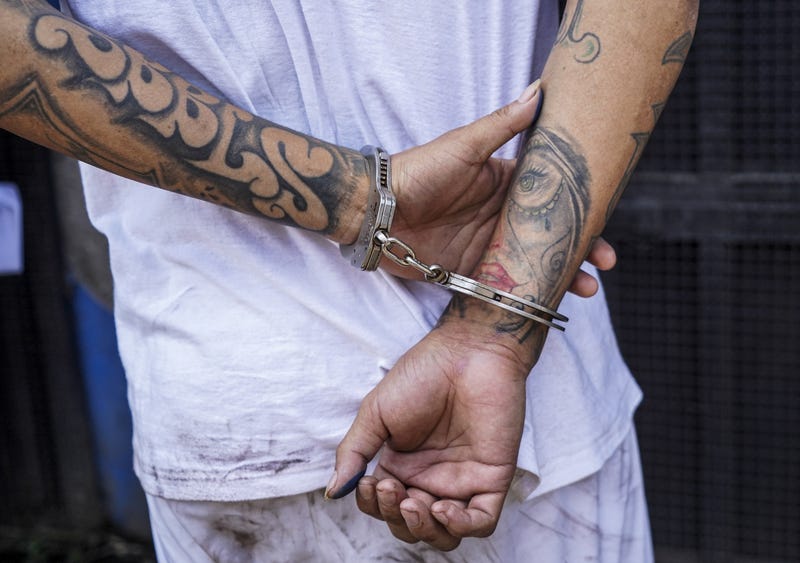 An MS-13 gang member is being escorted into a detention center.