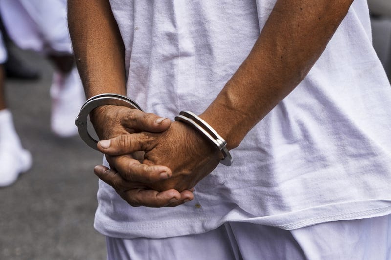 An MS-13 gang member is being escorted into a detention center.