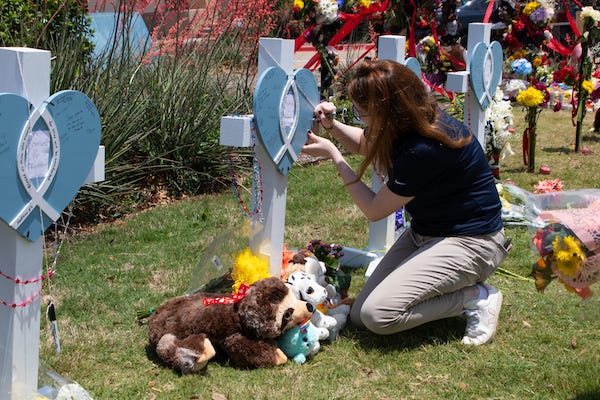A girl writes on a memory board to mourn victims of a mass shooting in front of an outlet mall in Allen, Texas, the United States, on May 8, 2023