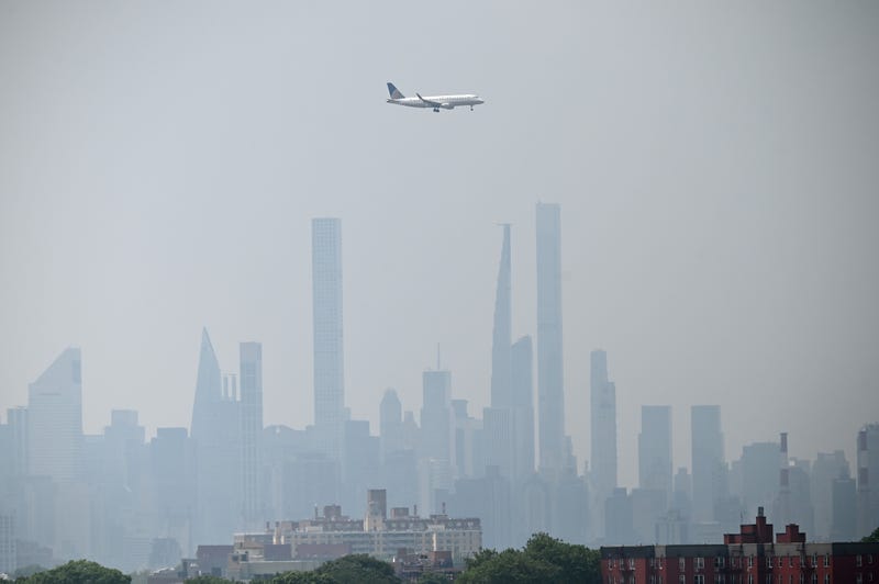 Haze and smoke from Canadian wildfires hover over the Manhattan skyline as a Continental Airlines plane makes a final approach at LaGuardia Airport in Queens on June 29, 2023