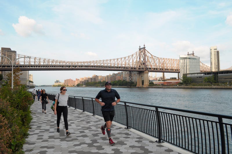 People walk and jog on the East River Esplanade also called the East River Greenway in Manhattan