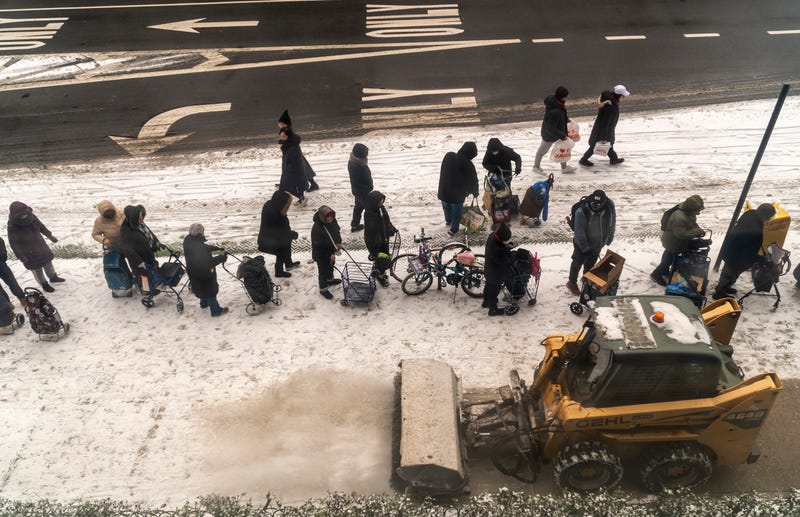 People line up in the snow for clothing and blankets at the Church of the Holy Apostles in Chelsea on Dec. 24, 2024