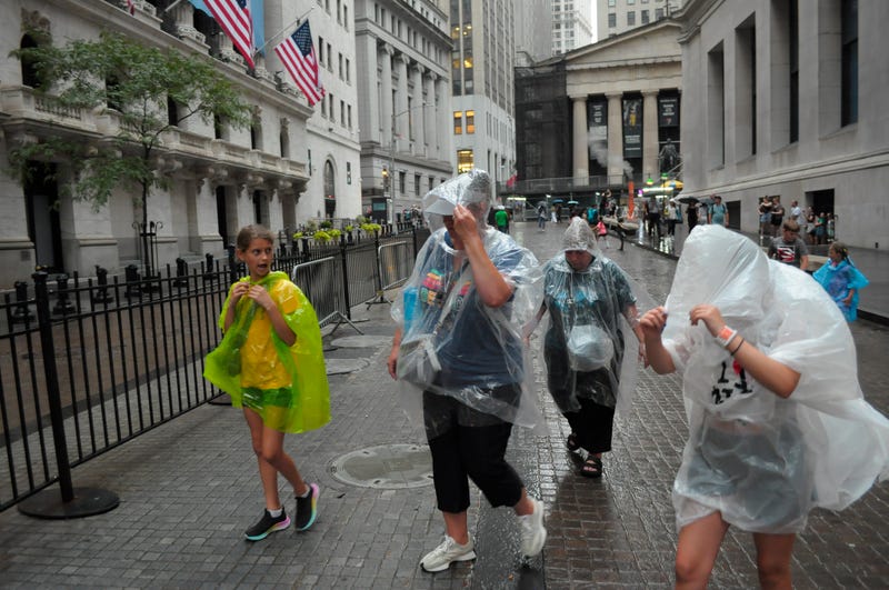 People wear rain ponchos and walk past the New York Stock Exchange in the Financial District on Wednesday