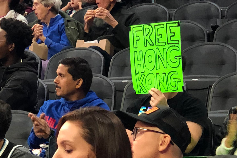 Sam Wachs is shown holding a sign reading "Free Hong Kong."