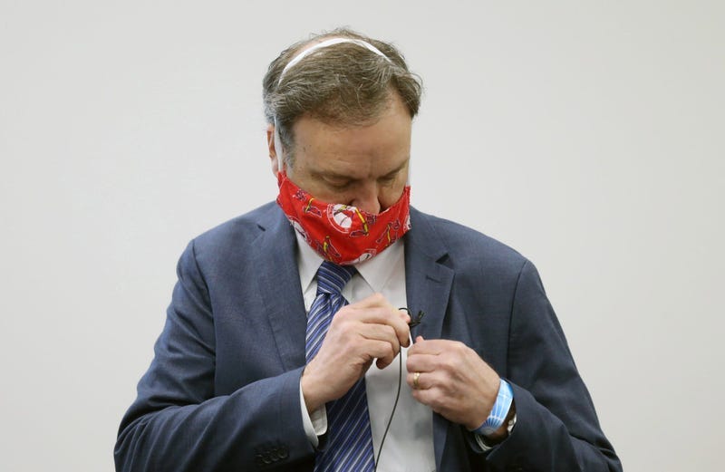 A masked Sam Page adjusts his microphone