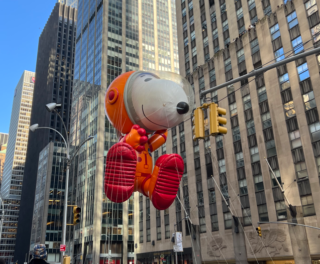 Snoopy in a space suit flying above New York City.