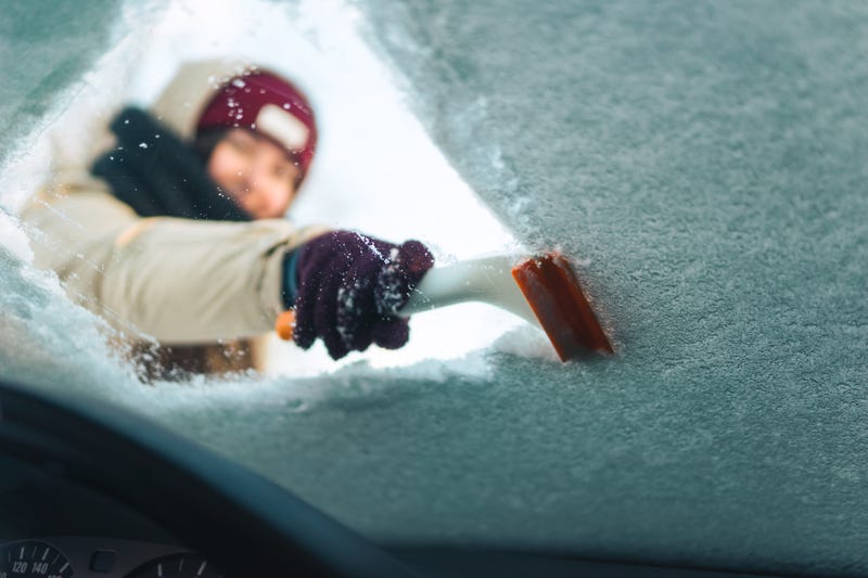 woman scraping snow from windshield