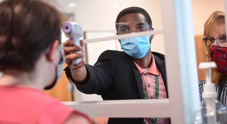 GCS Administrative Assistance Cameron Brice taking a reporter's temperature before a school tour