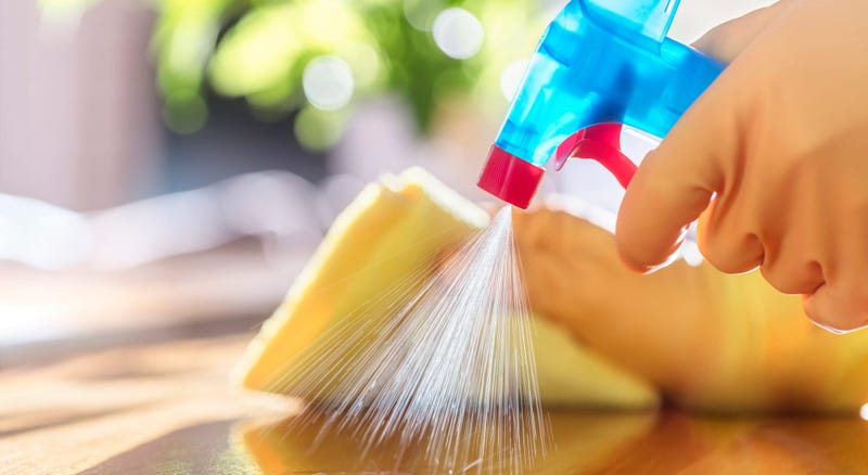 A person uses a spray bottle to clean a surface