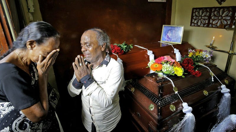 A Sri Lankan family mourns next to the coffins of their three family member, all victims of Easter Sunday bombing, in Colombo, Sri Lanka, Tuesday, April 23, 2019.