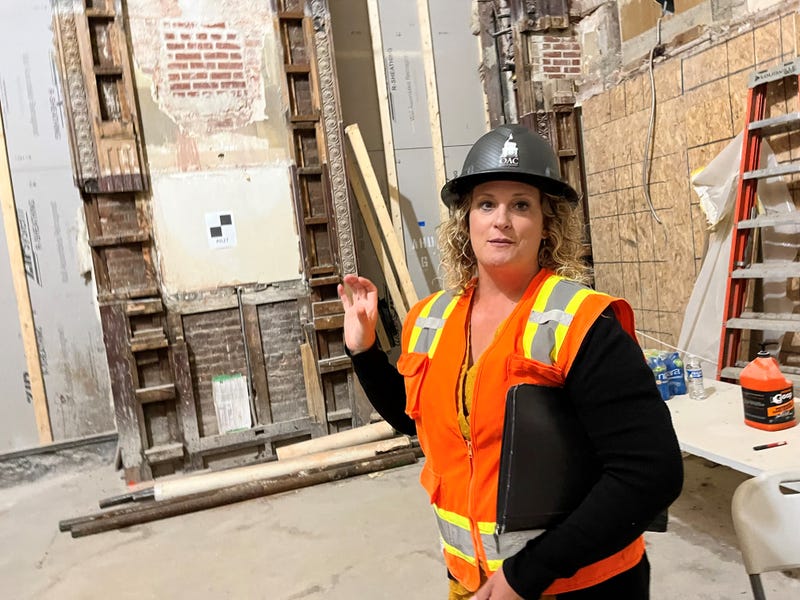 woman in orange vest and hard hat giving tour in construction zone