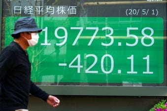 A man walks past an electronic stock board showing Japan's Nikkei 225 index at a securities firm in Tokyo Friday, May 1, 2020. (AP Photo/Eugene Hoshiko)