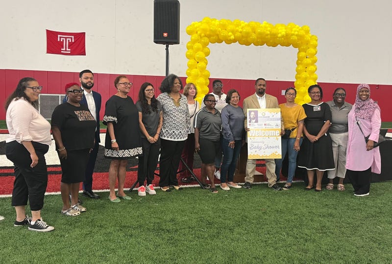 Pa. state Sen. Sharif Street (fifth from left) surrounded by attendees and exhibitors at a community baby shower event. He is holding a sign for the event.