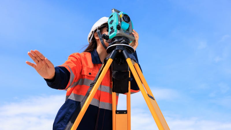 Engineer uses theodolite equipment working on construction site