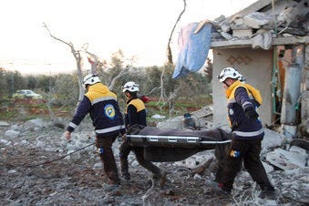 In this photo provided by the Syrian Civil Defense White Helmets, Syrian White Helmet civil defense workers carry a victim next to a destroyed house that was hit by Russian airstrike. (Syrian Civil Defense White Helmets via AP)