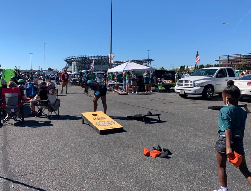 Eagles fans tailgating in the Lincoln Financial Field parking lot, including two fans playing cornhole.