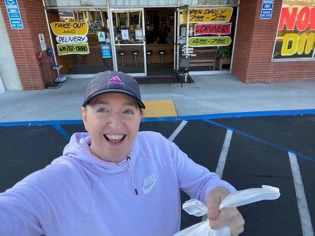 woman holding take-out in front of restaurant